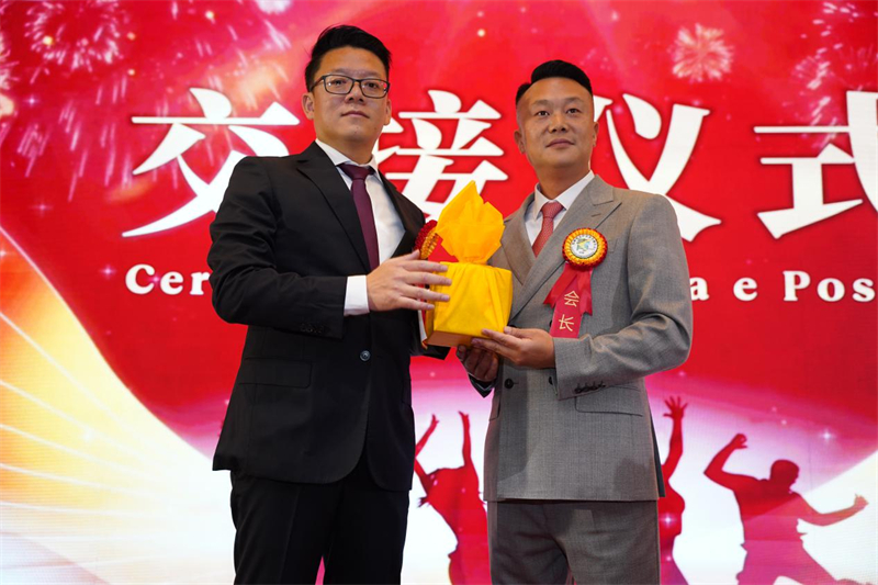巴西华人华侨青年联合会第五届、第六届会长周伟（左）和新一届会长邱垚伟进行会长印章交接。 巴西华人华侨青年联合会供图