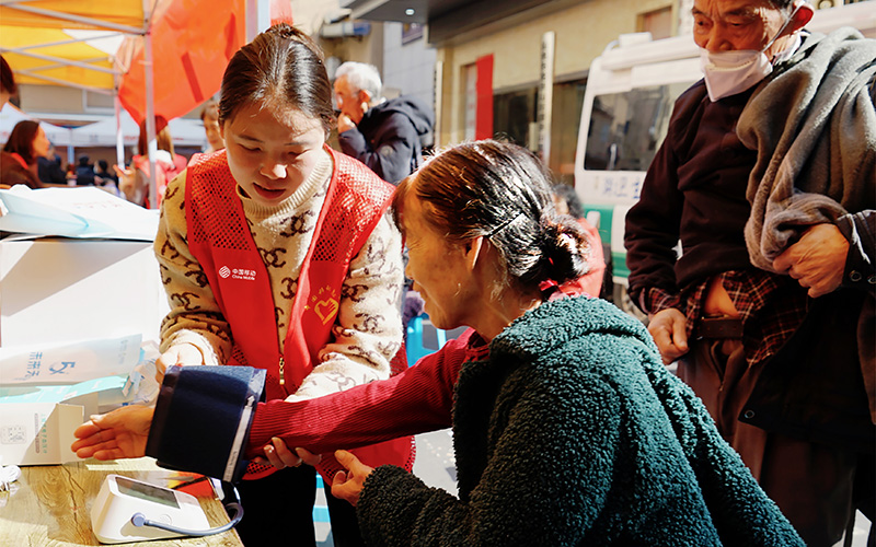 中国移动工作人员正细心地为老年人测量血压。