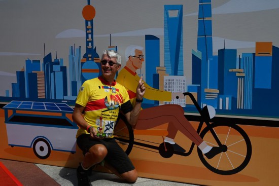 8月30日，在上海东方明珠广播电视塔城市广场，骑行爱好者克劳德·布鲁尔与自己的漫画形象背景墙合影。新华社记者 陈爱平 摄