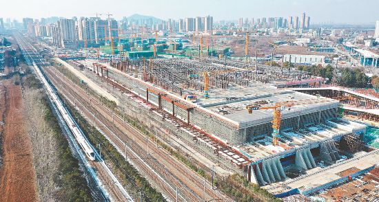 2025年1月16日，高速列车从合肥西站建设现场一旁驶过。项目工地上车辆穿梭，施工人员正在进行紧张的施工作业。