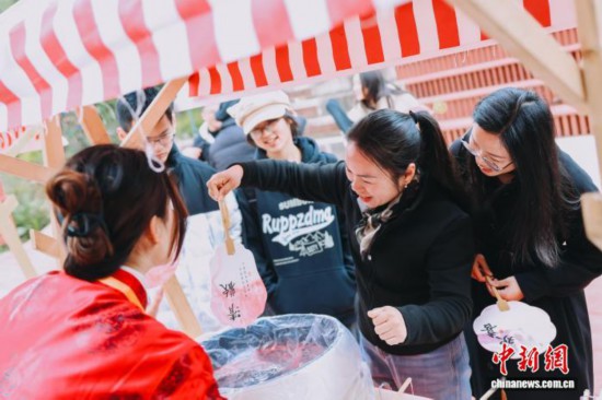 图为游客体验漆扇制作。翁榕飞 摄