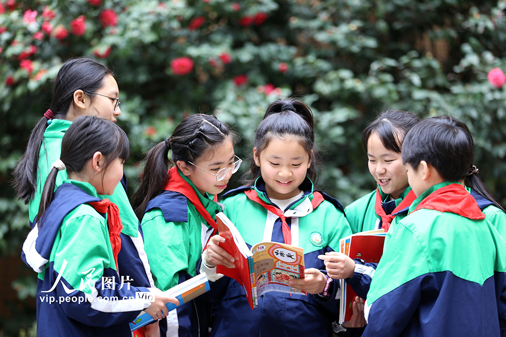 2026年3月1日,四川乐山市翡翠实验学校,学生们手持新领取的课本互相交流,以笑容迎接新学期的到来。李华时摄(人民图片网)