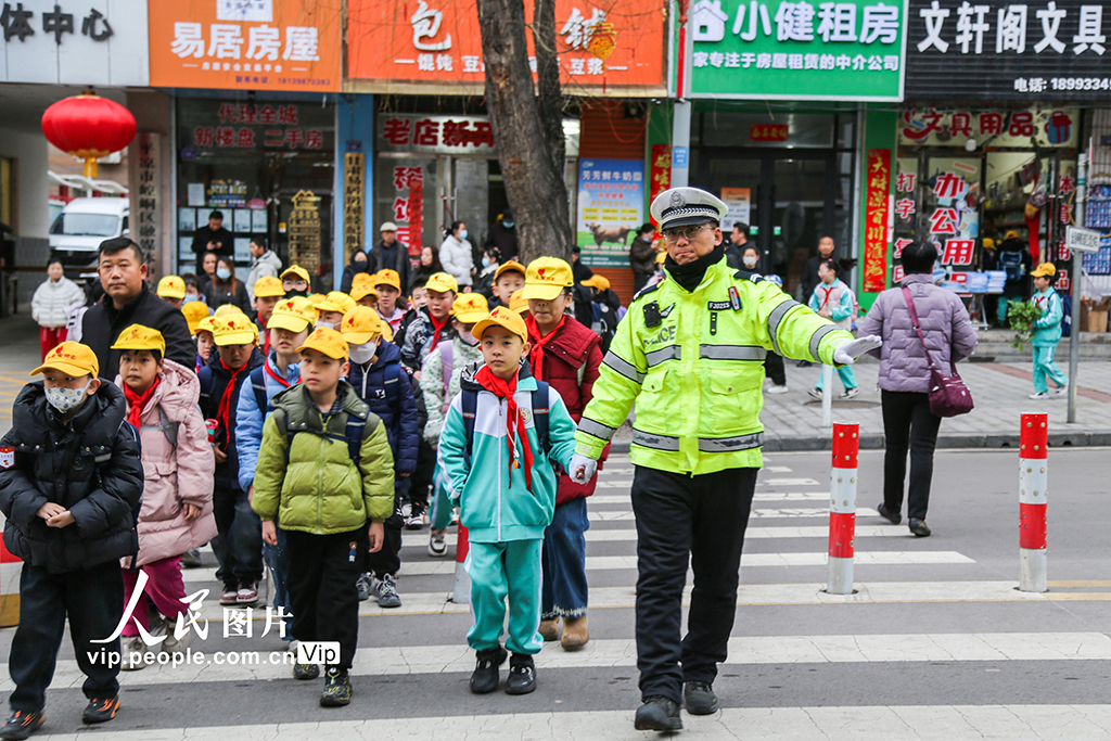 2026年3月2日,甘肃平凉市公安局崆峒分局交管大队执勤交警在学校门前的斑马线上,引导学生安全通过马路。郑兵摄(人民图片网)