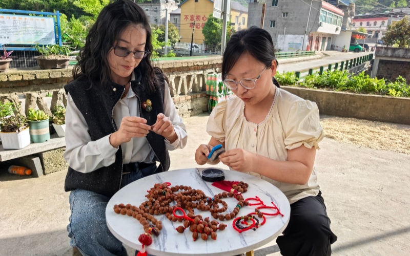 客户经理向黄德平学习核桃串编织技术。