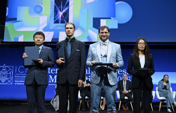 图为2026年7月23日,菲尔兹奖获得者中国数学家邓煜(左一)、王虹(右一)、美国数学家约翰·帕登(左二)和加拿大数学家雅各布·齐默曼在美国费城举行的2026年国际数学家大会开幕式上合影。新华社记者李睿摄